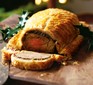 Sliced beef wellington on a wooden board