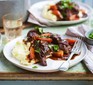 Beef stew with vegetables on mashed potato on plate with fork