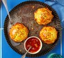 Three round pastry pies on a fluted tin with a small bowl of mango chutney on the side