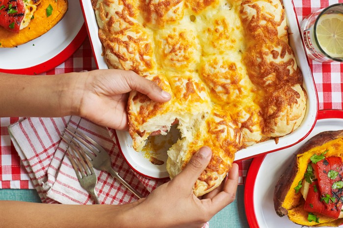 Someone pulling cheese-covered garlic rolls apart